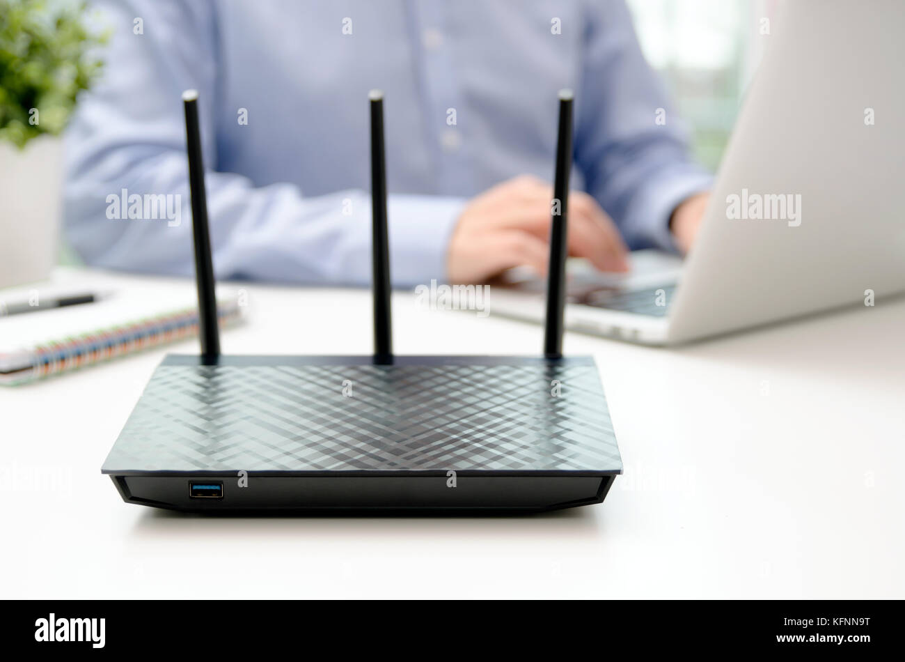Routeur sans fil et l'homme à l'aide d'un laptop in office. Le routeur large bande sans fil wifi Téléphone portable accueil concept Banque D'Images
