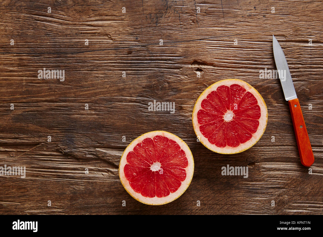 Pamplemousse bio sains en tranches avec un couteau orange Banque D'Images