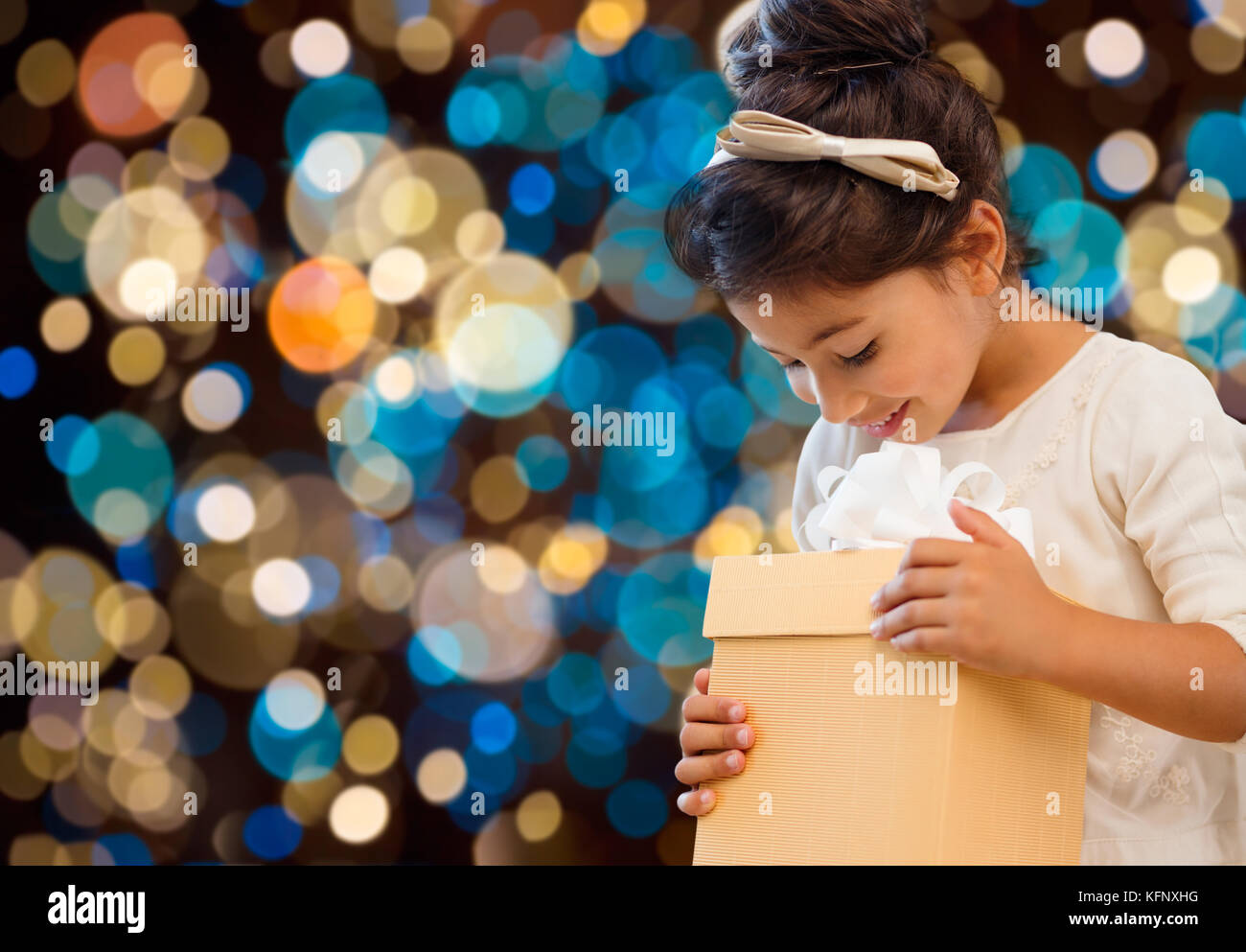 Smiling little Girl with gift box sur lights Banque D'Images