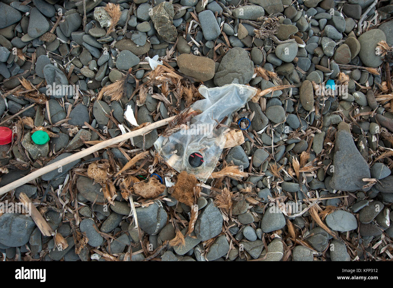 Un sac à vin en plastique et autres objets en plastique échoué sur une plage de galets sur l'île de Minorque en méditerranée Banque D'Images