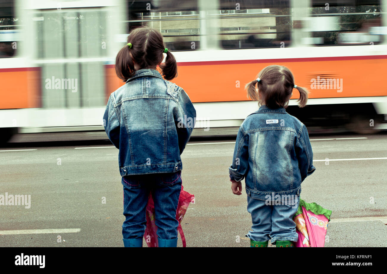 Deux petites filles (sœurs) attendant de traverser la rue dangereuse. Vue arrière. Banque D'Images