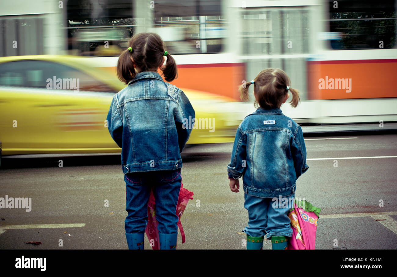 Deux petites filles (sœurs) attendant de traverser la rue dangereuse. Vue arrière. Banque D'Images