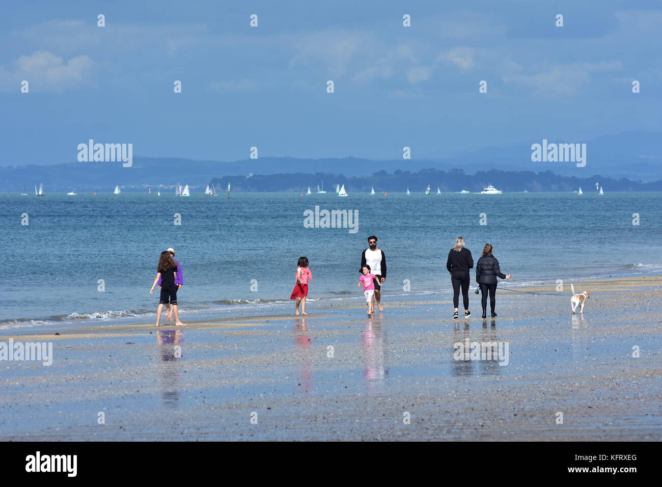 Personnes marchant sur une plage de l'océan de sable de Takapuna à Auckland par jour nuageux. Banque D'Images