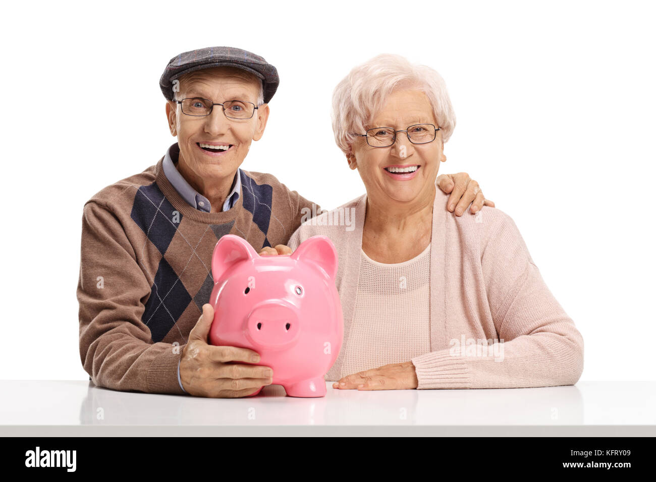 Couple avec une tirelire assis à une table regardant la caméra et smiling isolé sur fond blanc Banque D'Images