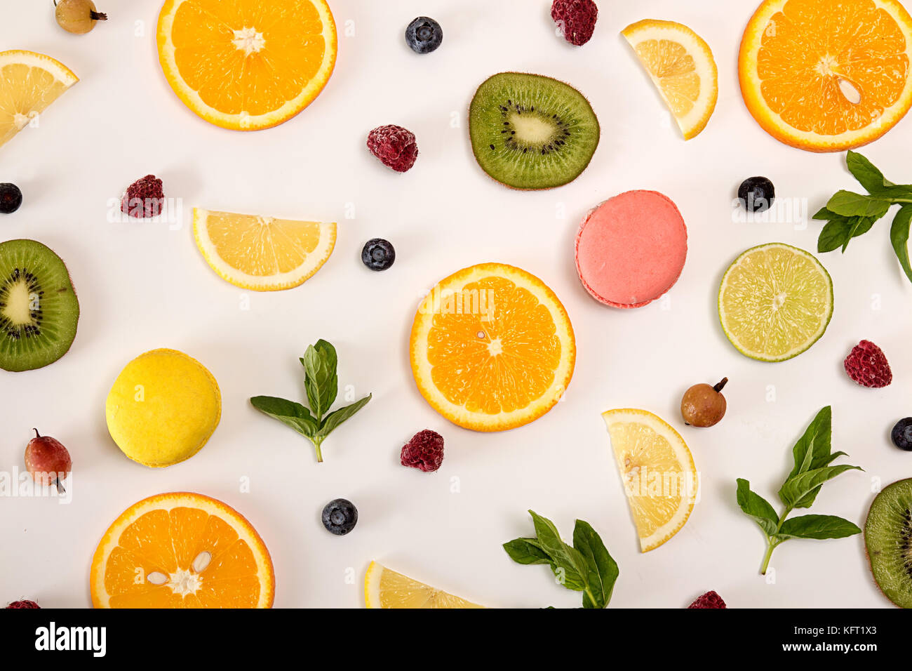 Mise à plat de la vie toujours avec ses macarons, fruits rouges, menthe et agrumes et autres fruits : fruits orange ; chaux ; Citron, kiwi sur fond blanc. Toujours tendance pop art Banque D'Images