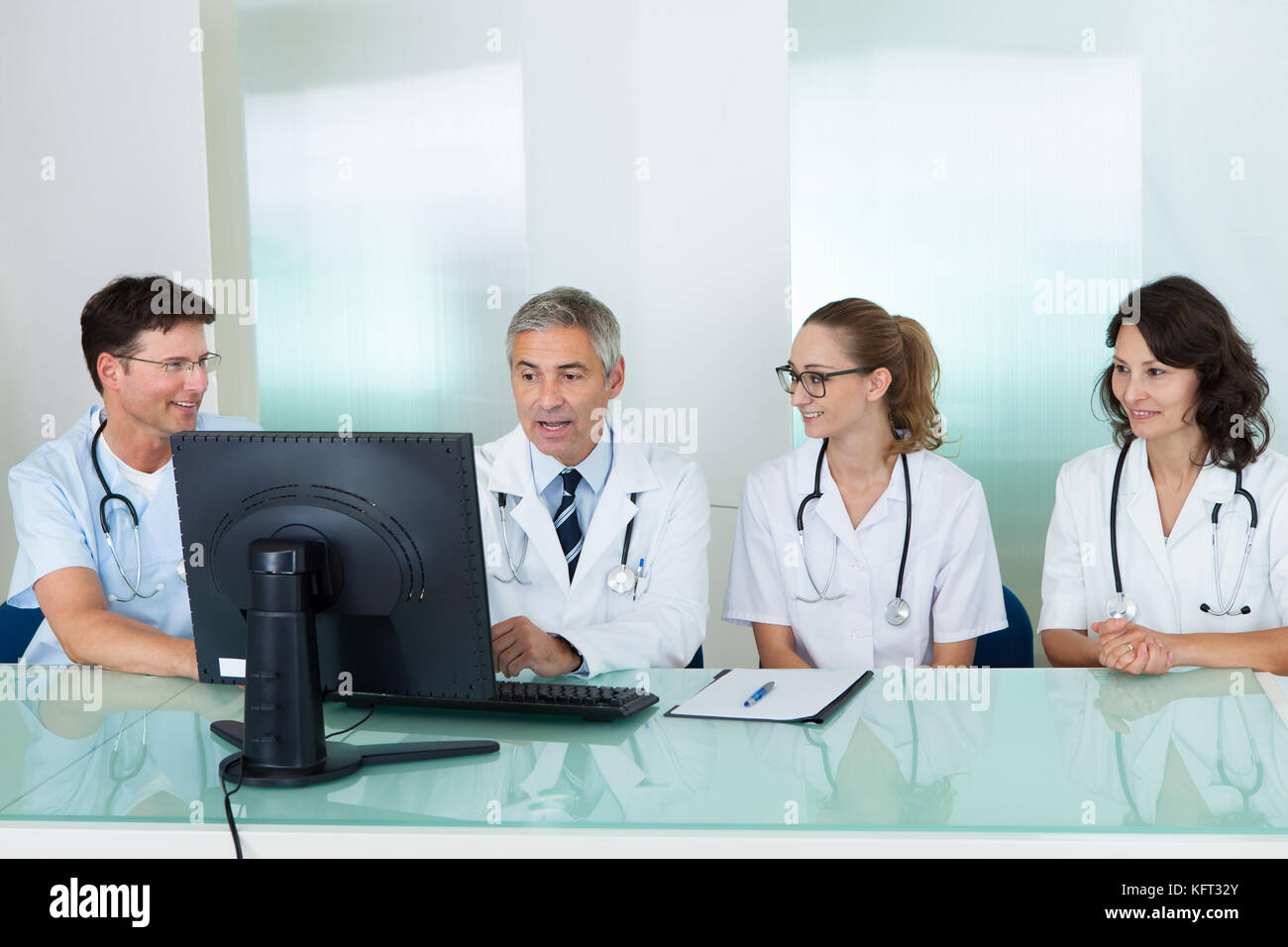 Les médecins ayant une réunion assis à une table en face d'un ordinateur à discuter des études de cas Banque D'Images