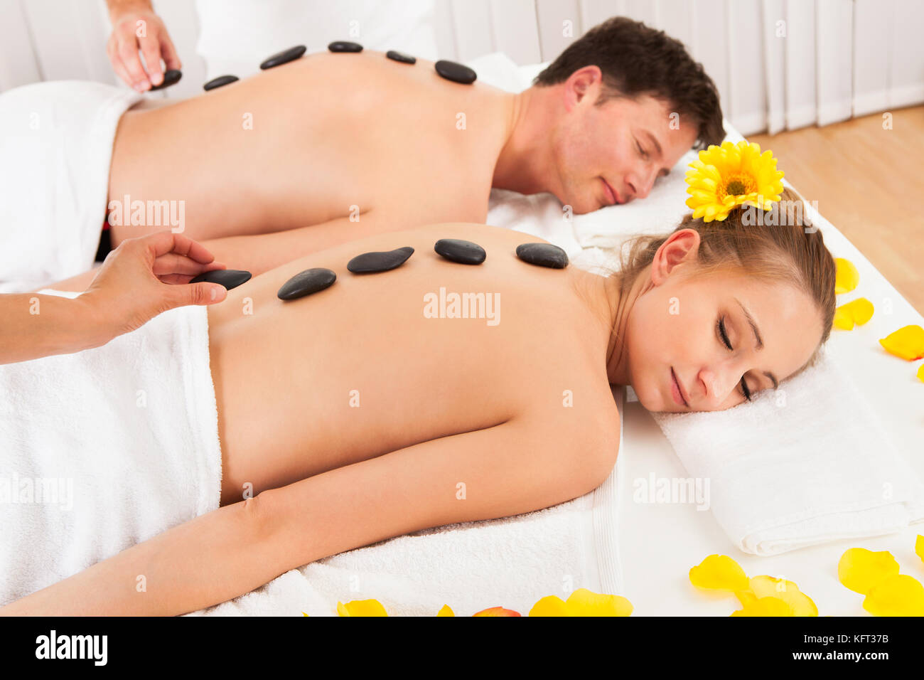 Couple having a massage aux pierres chaudes de traitement dans un spa relaxant que la chaleur des pierres détend les muscles Banque D'Images
