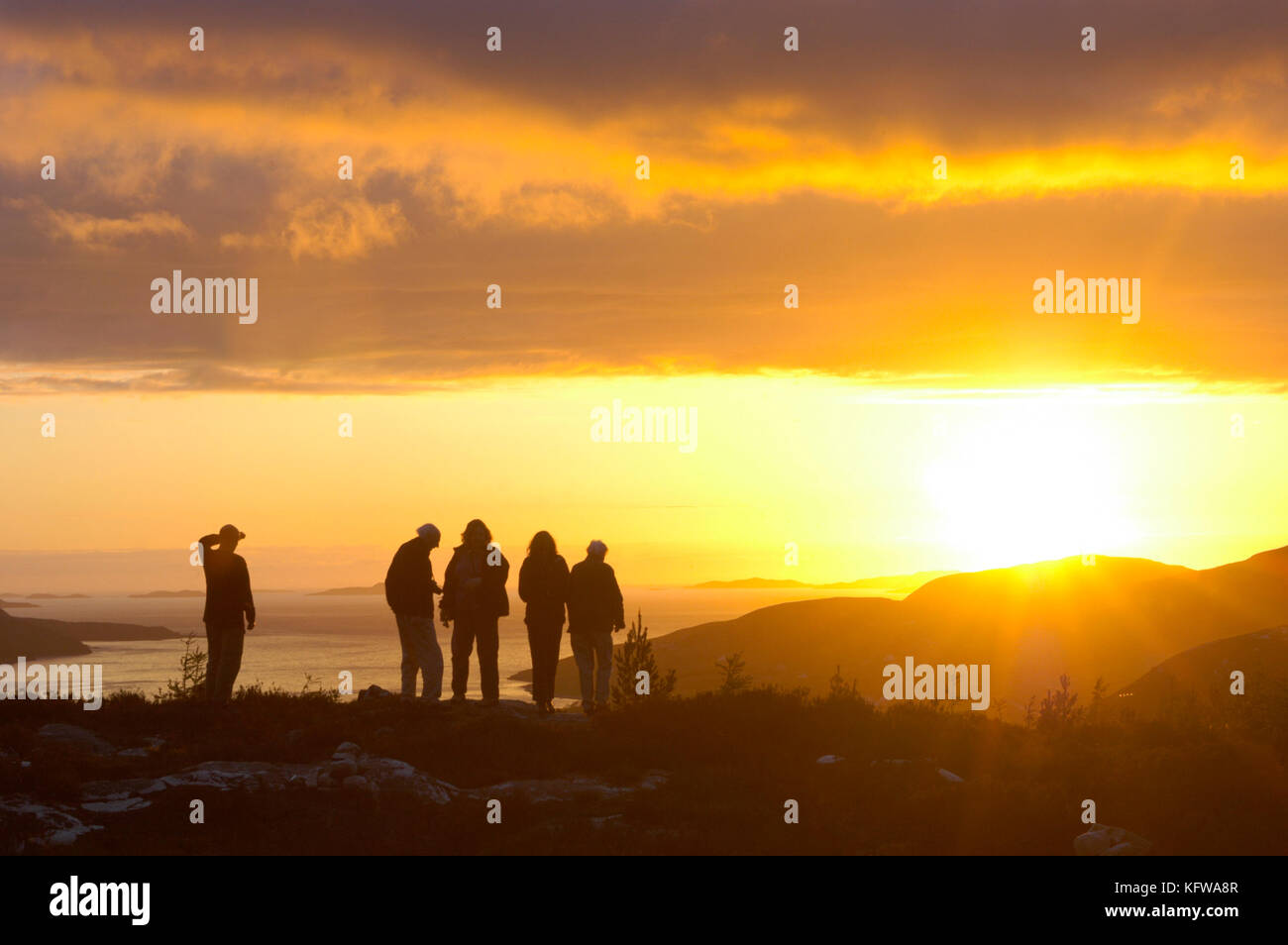 Un groupe de jeunes visiteurs admirant le coucher de soleil d'automne sur le Loch Broom et ullapool dans Wester Ross, nord-ouest de l'Ecosse Banque D'Images