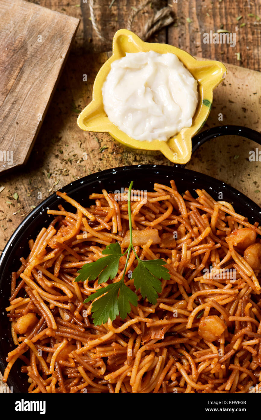 Capture d'un grand angle d'une fideua typique espagnol, une casserole de nouilles aux fruits de mer, paella dans une casserole et sauce aïoli dans un mortier jaune sur un rustique en t Banque D'Images