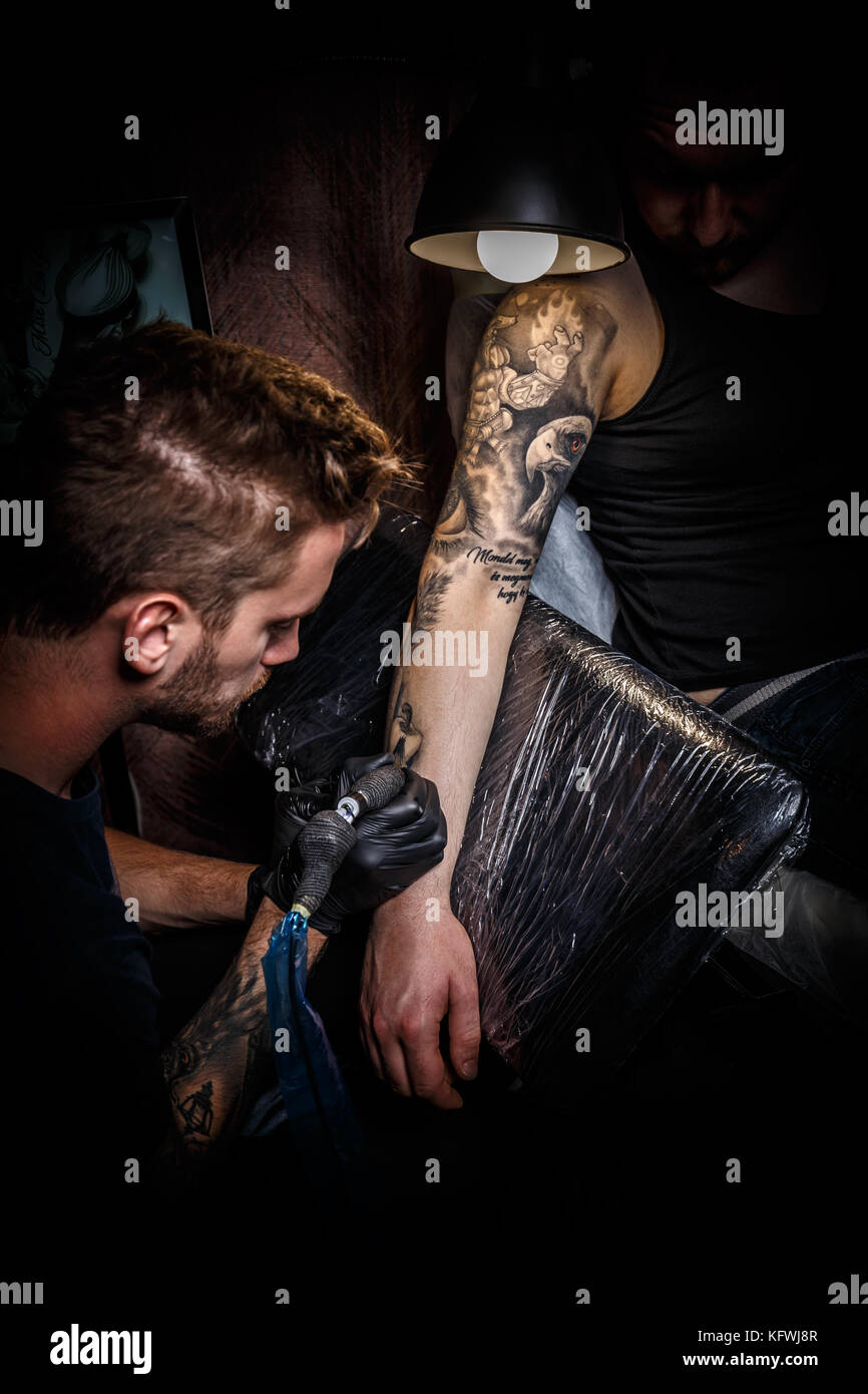 Le barbu tatoueur fait un tatouage sur la main d'un homme Banque D'Images