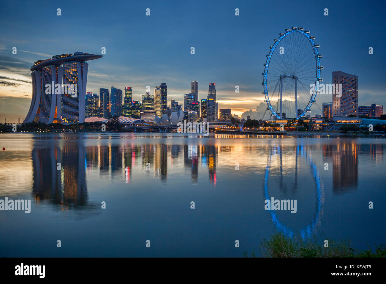 Horizon de Singapour avec Marina Bay Sands, le CBD et le Singapore Flyer, le tout reflété dans Marina Bay et illuminé au crépuscule. Banque D'Images