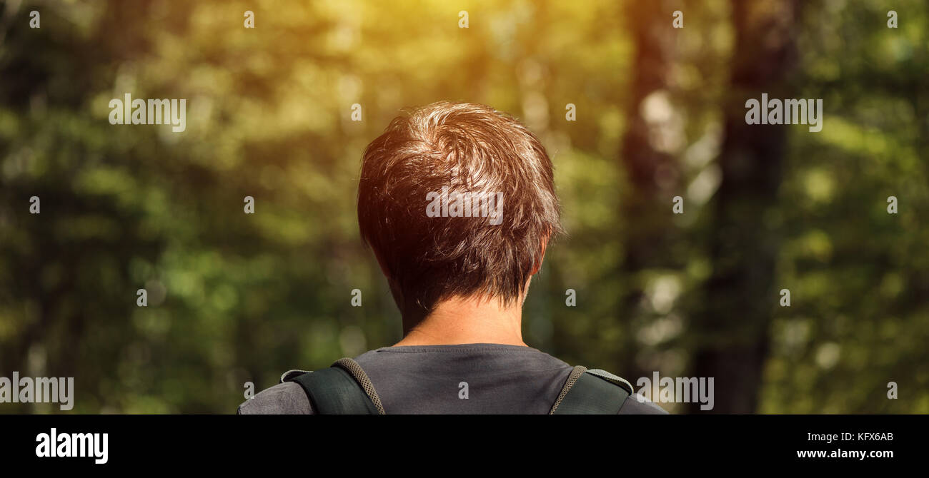 Vue arrière du sac à dos avec l'homme de race blanche adultes bénéficiant d'une promenade dans le parc aux beaux après-midi d'été. Bonne hygiène de vie, des loisirs et de la nature aimer Banque D'Images