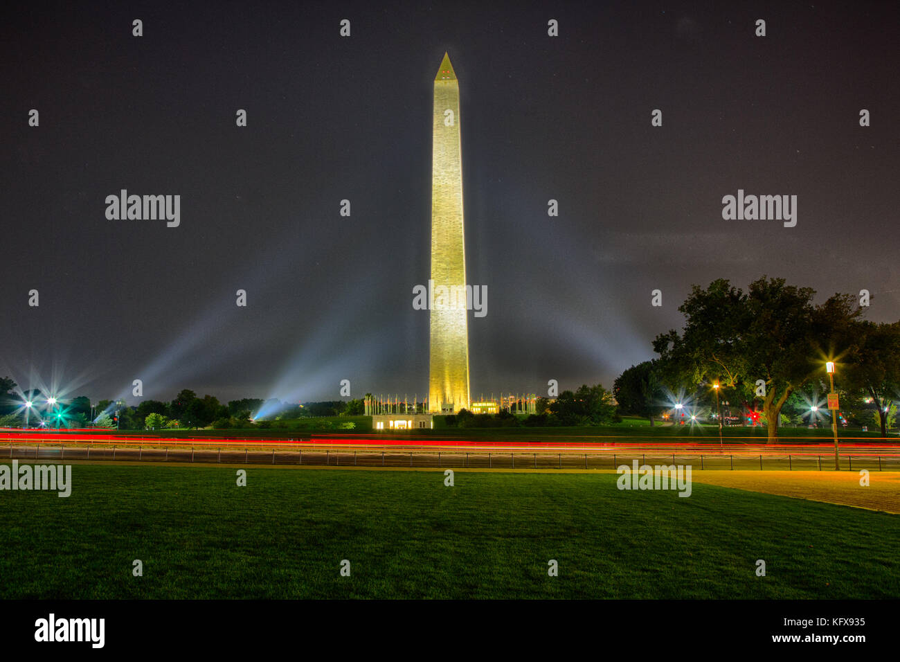 Le Washington monument illuminé en une nuit d'été avec des drapeaux autour de la base. Banque D'Images