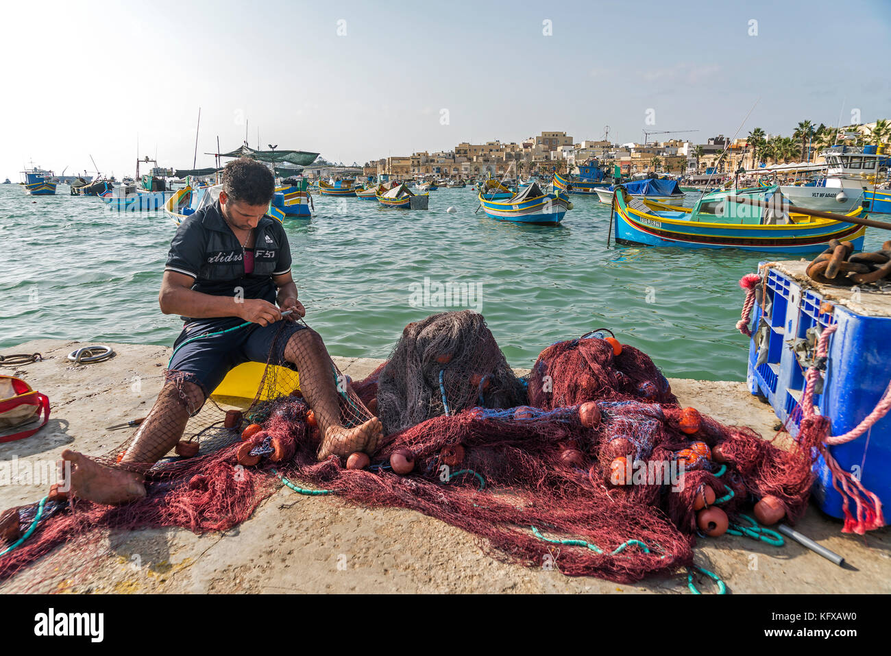 Fischer refiert sein Netz im Hafen von Marsaxlokk, Malte | pêcheur réparant son filet dans le port de Marsaxlokk, Malte Banque D'Images