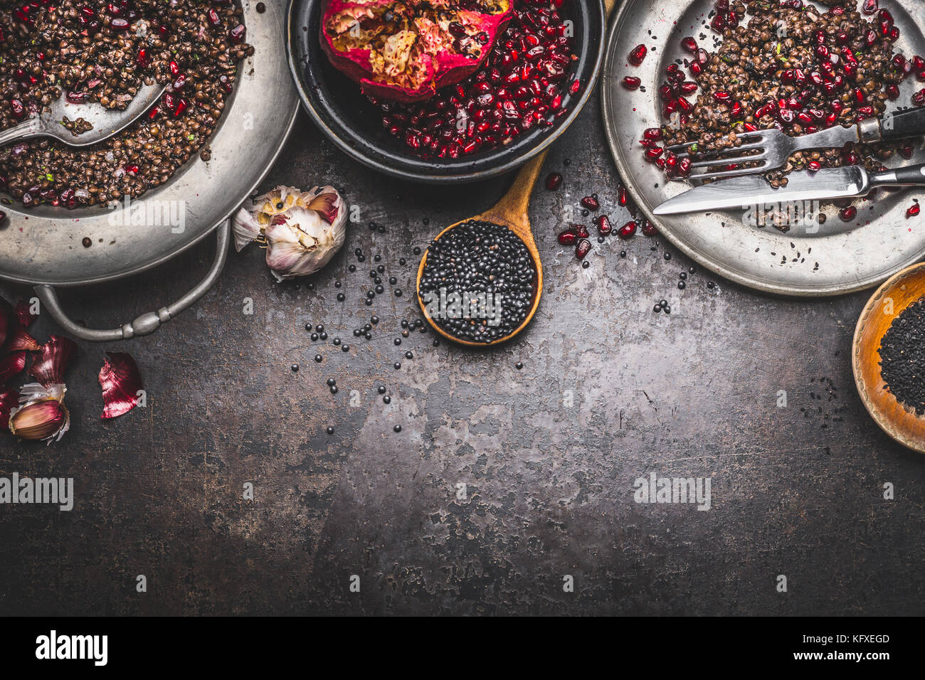 Salade de lentilles beluga noir préparation à la grenade sur fond rustique foncé, vue du dessus, border Banque D'Images