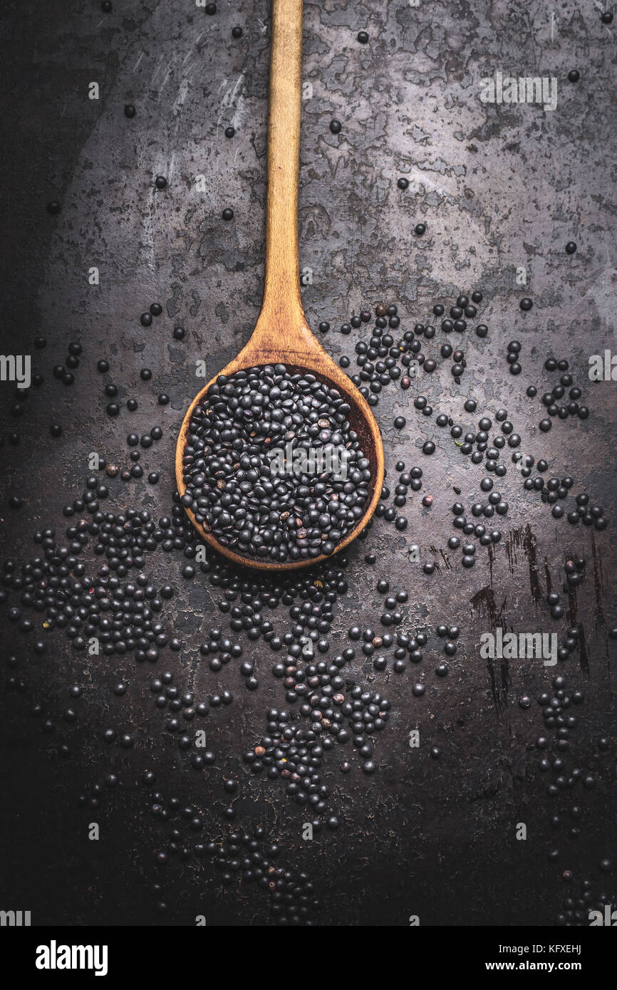 Graines de lentille beluga noir dans la cuisine en bois foncé sur fond rustique cuillère, vue du dessus Banque D'Images