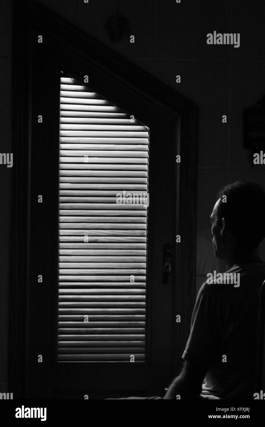 Porte de placard avec lumière rouge à l'intérieur de l'éclairage d'un homme assis en regardant la porte. image en noir et blanc. Banque D'Images
