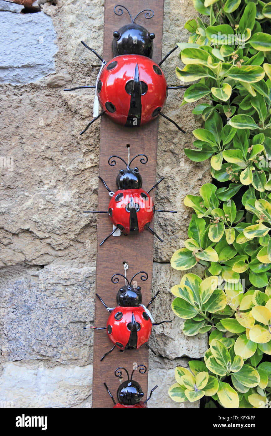 Ornements de jardin en forme de coccinelles , affiché sur le mur de pierre, Espagne Banque D'Images