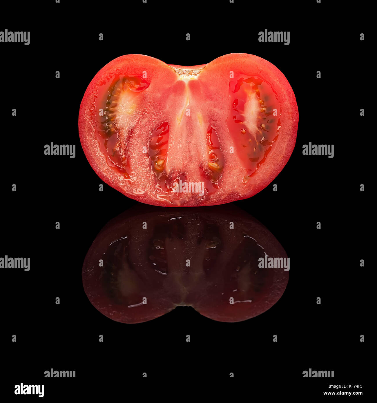 La moitié de la tomate rouge coupe libre isolé sur fond noir brillant avec du vrai réflexion. Vue de côté Banque D'Images