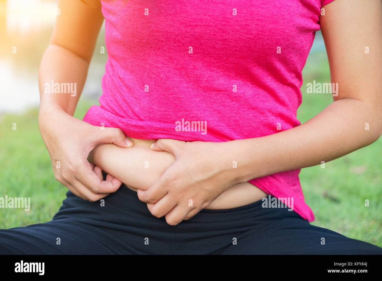 Chubby woman hand holding sa propre graisse du ventre Banque D'Images
