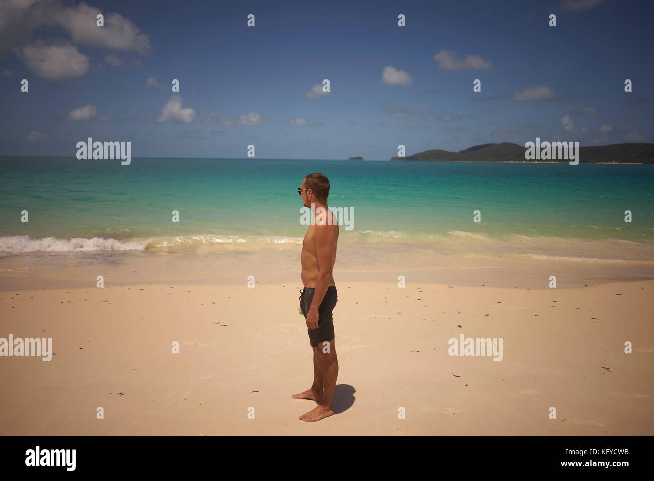 Jeune homme bien formé est debout sur la plage donnant sur la mer Banque D'Images