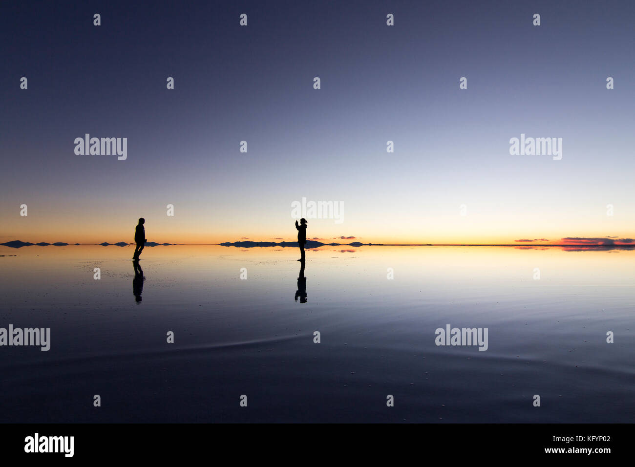 Deux amis dans le désert plat de sel d'Uyuni en saison des pluies Banque D'Images