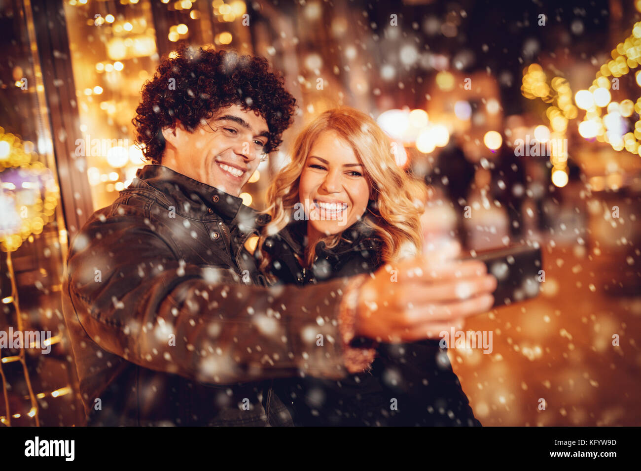 Deux belles jeunes gais dans la rue selfies avec flocons de neige autour. Banque D'Images