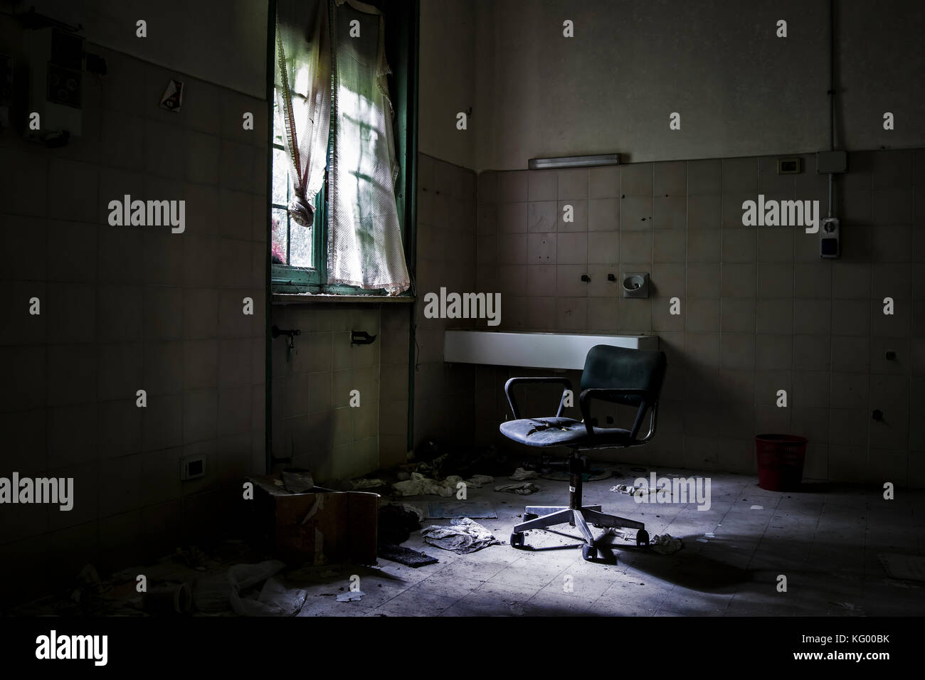 Un coup effrayant d'une chaise dans l'obscurité, dans une chambre d'un hôpital psychiatrique abandonné, avec un peu d'environnement. Banque D'Images