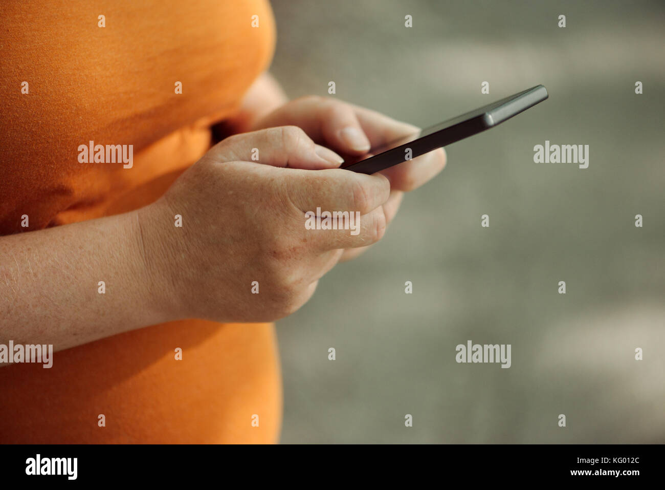 Pregnant woman texting outdoors on park bench, adulte femelle de race blanche à l'aide de téléphone mobile pendant la grossesse Banque D'Images