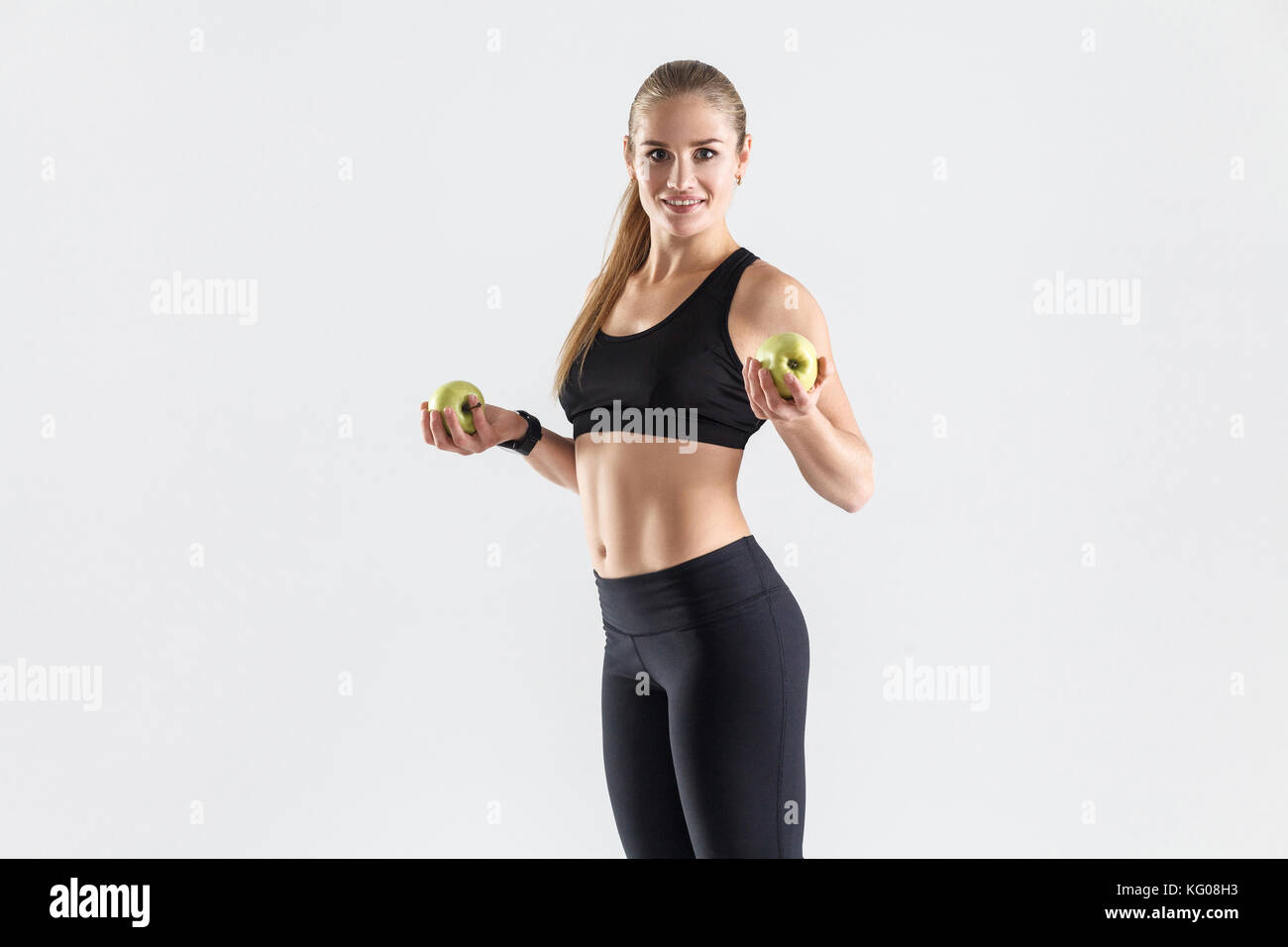 Des aliments sains, des aliments frais, le régime alimentaire concept. athletic woman holding apple vert biologique, rugueux et smiling at camera Banque D'Images