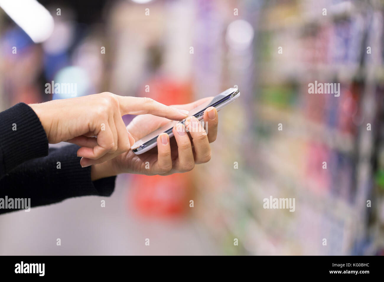 Woman using mobile phone tout en shopping in supermarket Banque D'Images