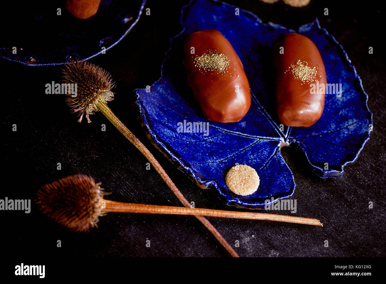 Gâteau de pommes de terre au chocolat avec de la poudre d'or sur le bleu profond de la plaque. Une œuvre d'art culinaire Banque D'Images