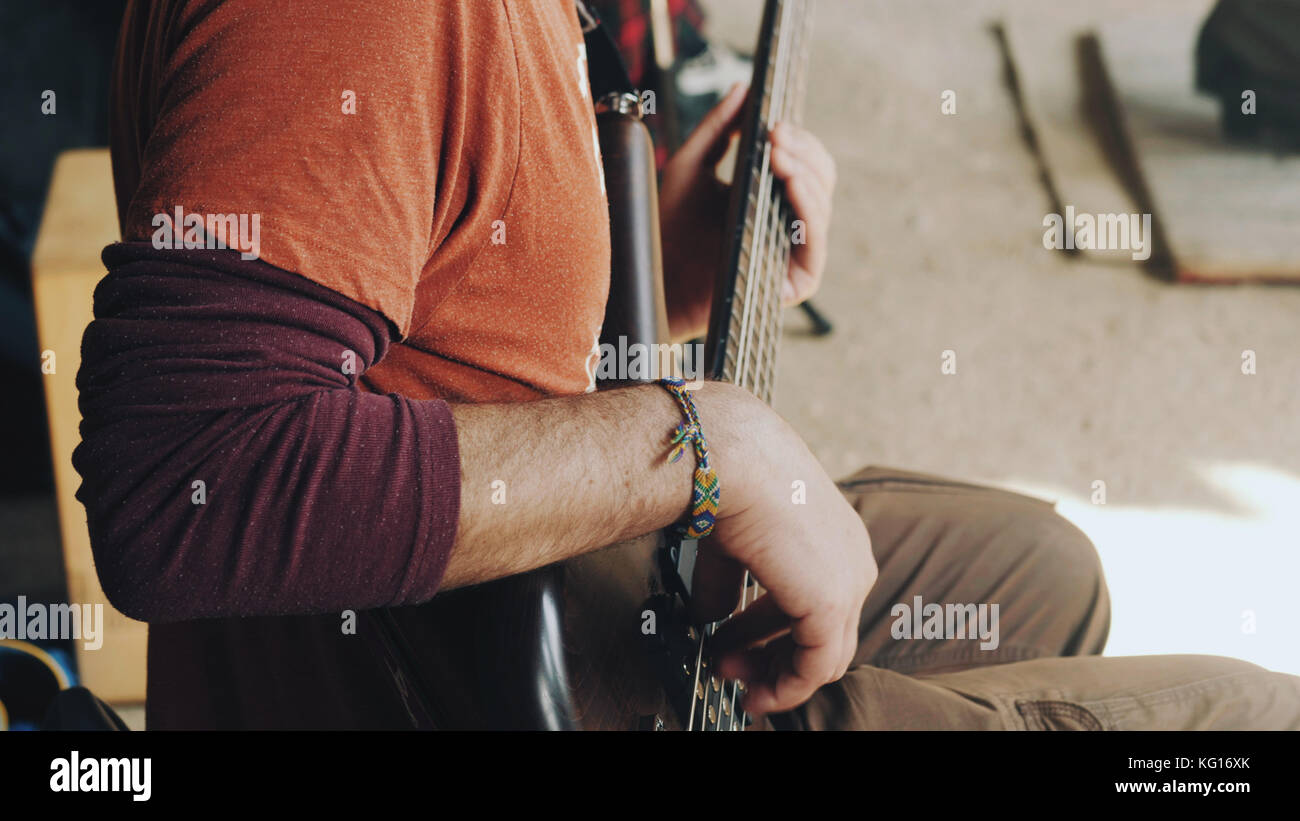 Homme jouant de la guitare basse au concert dans la rue. Vue rapprochée du guitariste joue sur l'instrument de musique en bois brun avec un musicien de rue. Banque D'Images