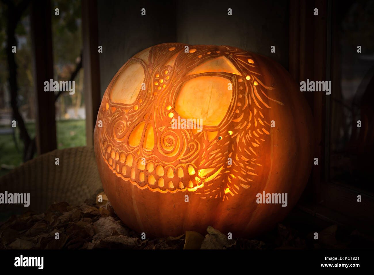 Sculpté artistiquement glowing jack-o-lanterne sur la table d'affichage avec des feuilles pour l'halloween Banque D'Images