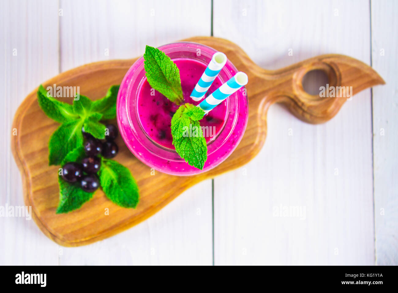 Les smoothies de cassis dans un bocal en verre avec paille sur une table en bois blanc Vue de dessus. Banque D'Images