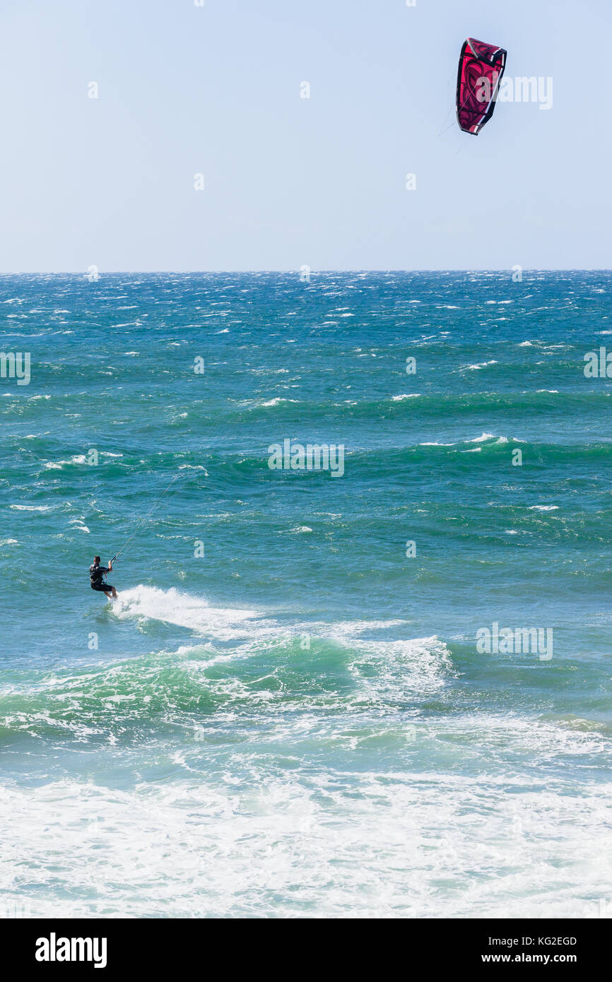 Kite surfer tête vers l'horizon à travers les vagues de l'océan. Banque D'Images