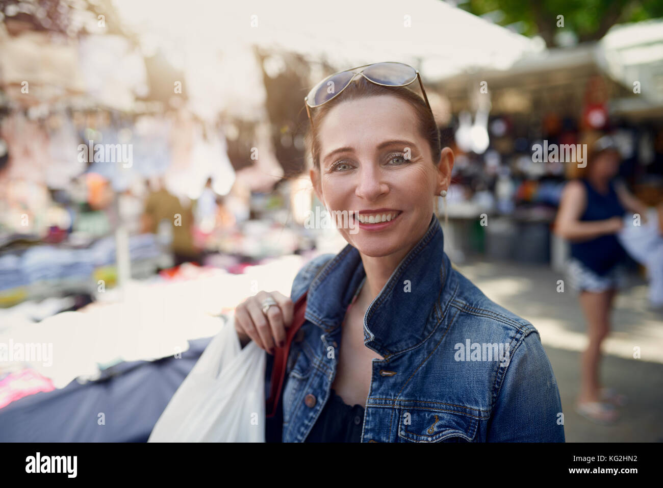 Femme élégante attrayante happy shopping dans un marché plein air debout regardant la caméra avec un large sourire amical chaud Banque D'Images