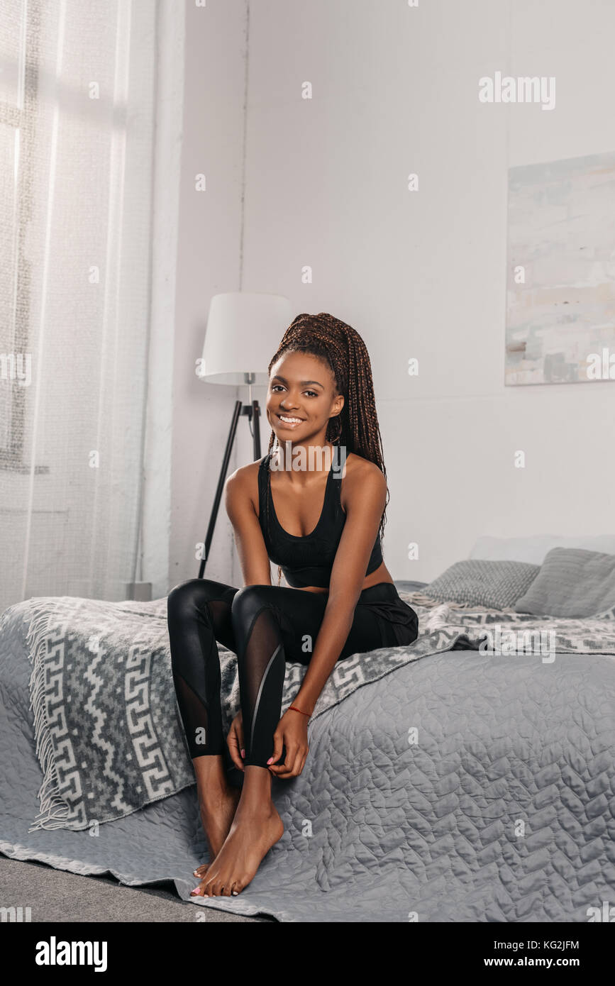 Woman in sportswear sitting on bed Banque D'Images