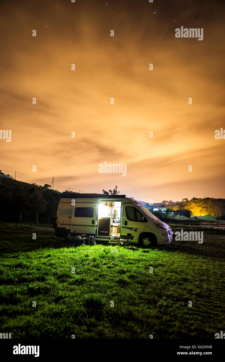 Photo nocturne d'un camping-auto stationné sur un terrain d'herbe Banque D'Images