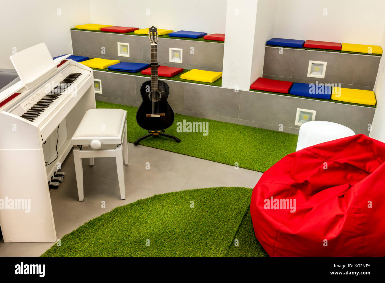 La musique moderne, avec piano blanc et noir guitare ; sièges colorés et  pouf Photo Stock - Alamy