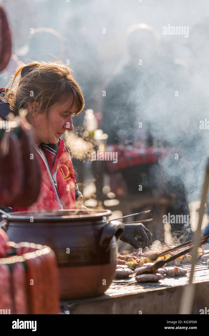 Pernik, Bulgarie - 27 janvier 2017 : femme cuisinière en tablier rouge est en train de préparer un barbecue avec soin à town square à surva, le festival international de la t Banque D'Images