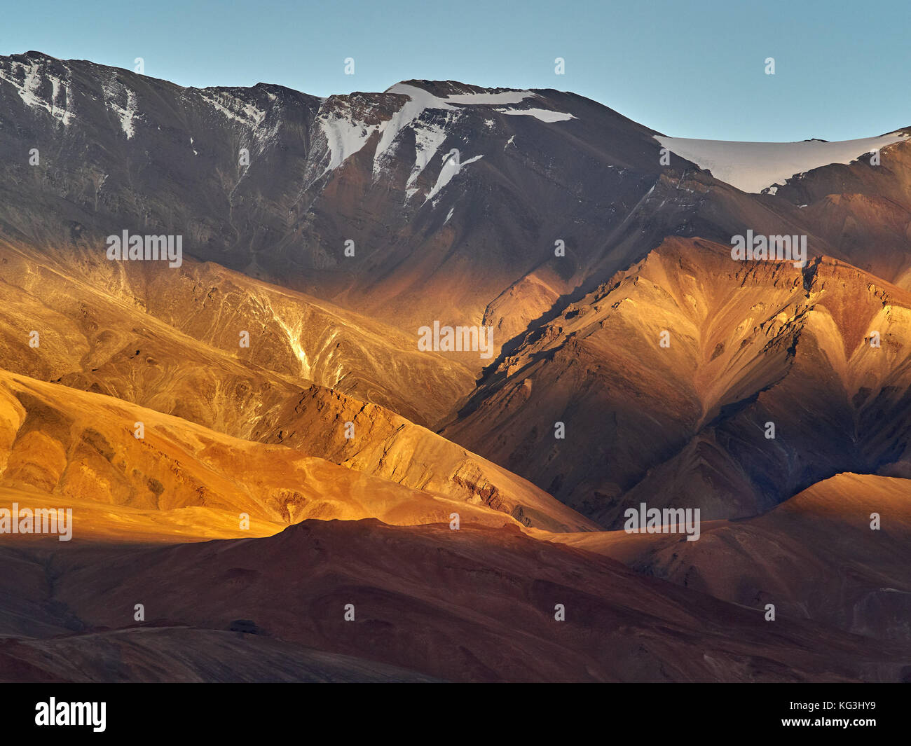 Coucher du soleil dans les hautes montagnes : les derniers rayons de soleil  couleur les pentes des collines dans une couleur orange vif, sur des tops  reposent les restes de neige, l'été