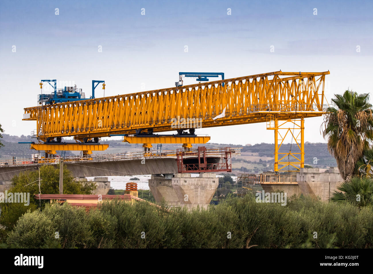 La construction d'un pont ou d'autoroute Autostrada avec grande grue à portique levage en sections de route entre piliers. la Sicile, Italie Banque D'Images