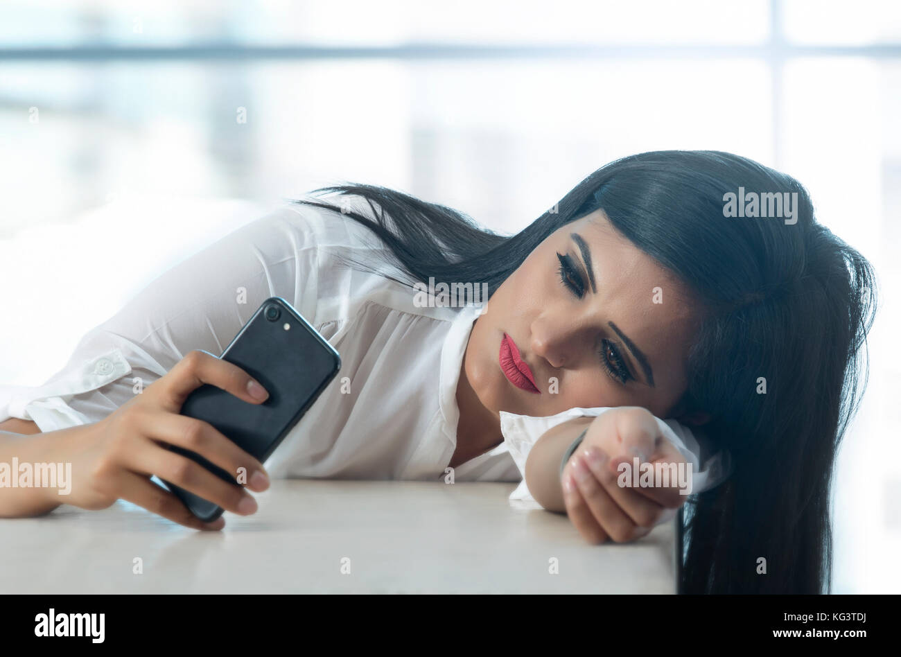 Businesswoman leaning on table et using mobile phone Banque D'Images
