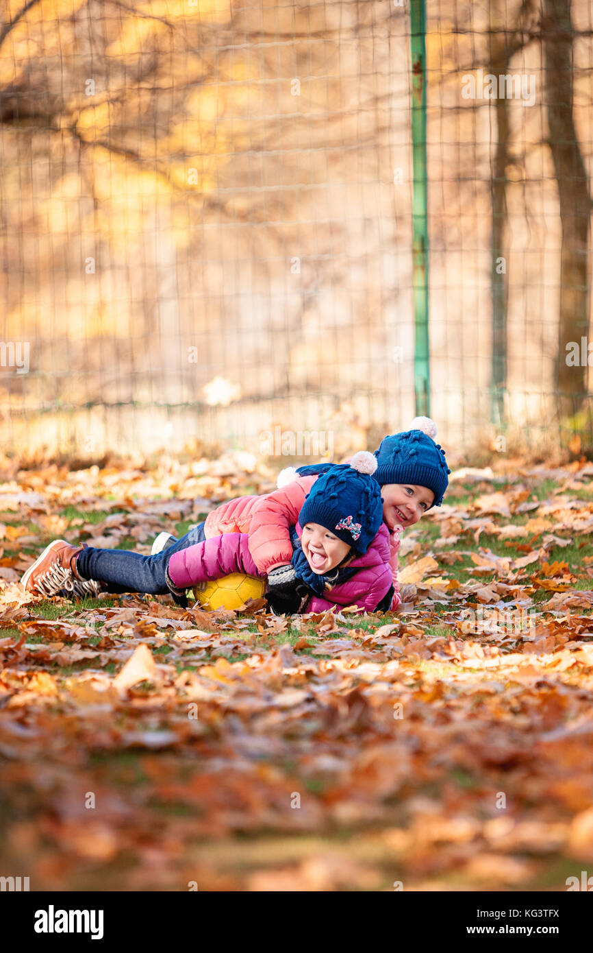 Les deux petites filles jouant dans les feuilles d'automne Banque D'Images