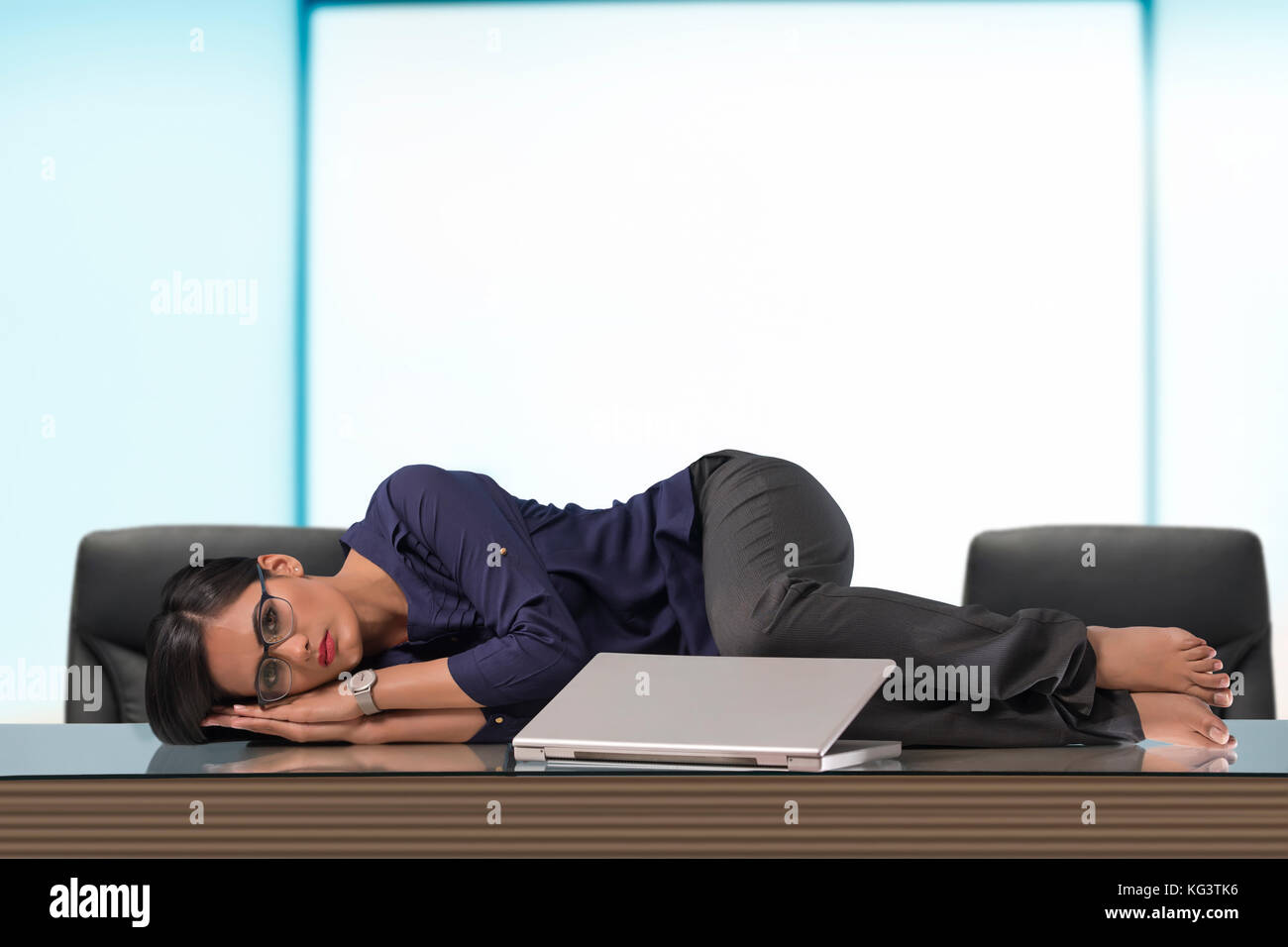 Businesswoman lying on desk in office Banque D'Images