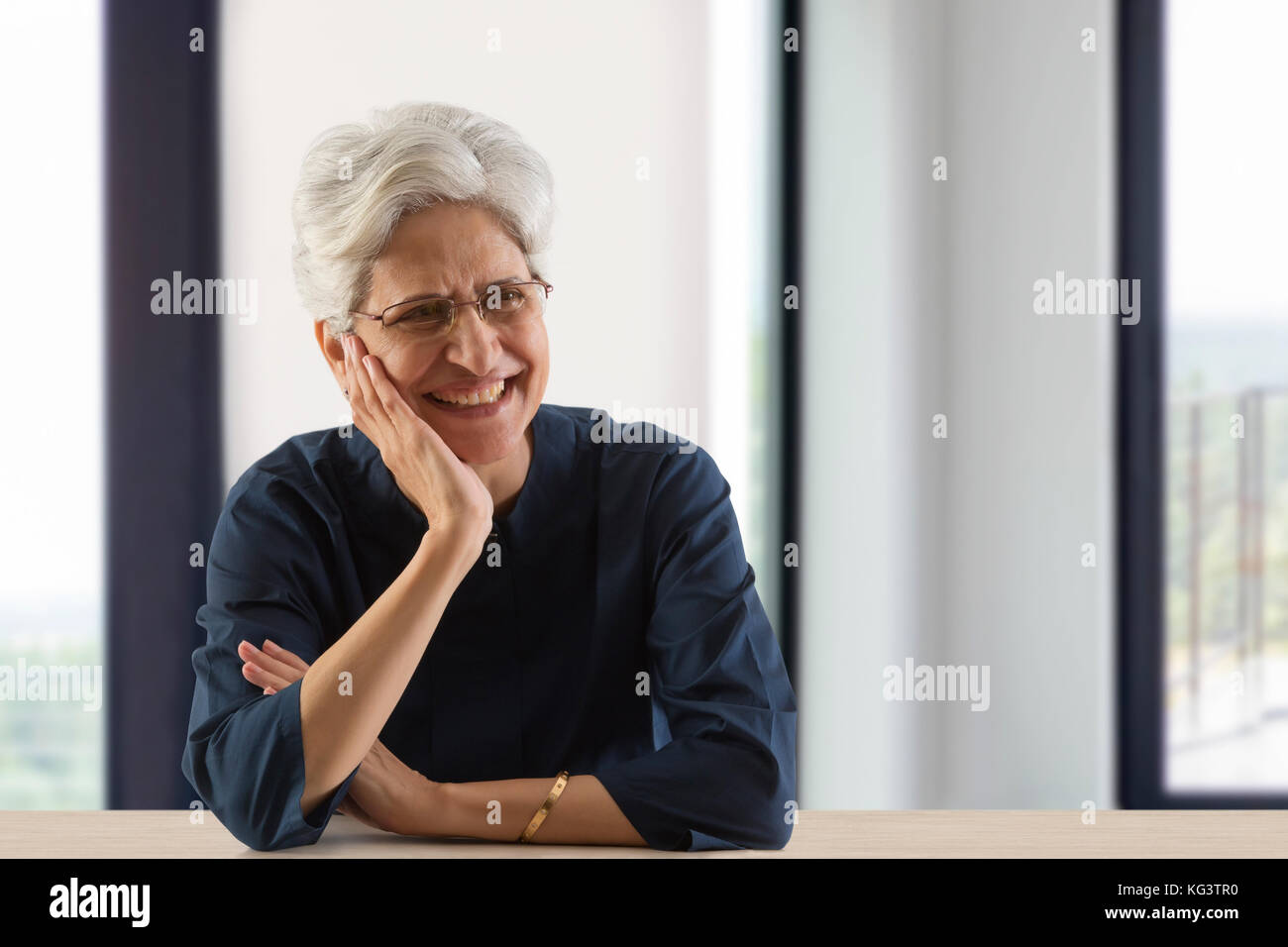 Smiling senior woman with hand on chin looking away Banque D'Images
