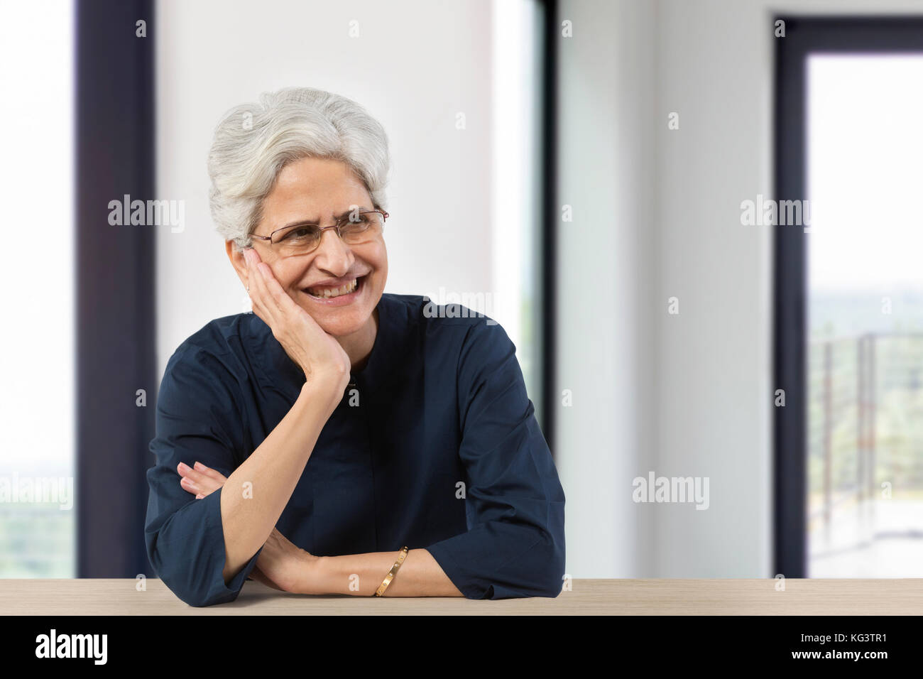 Happy senior woman with hand on chin looking away Banque D'Images