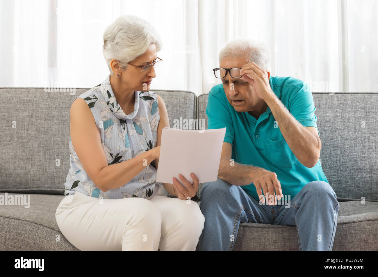 A Senior couple sitting on sofa document Banque D'Images