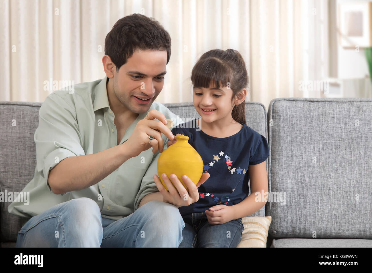 Père et fille mettant l'argent dans piggybank Banque D'Images